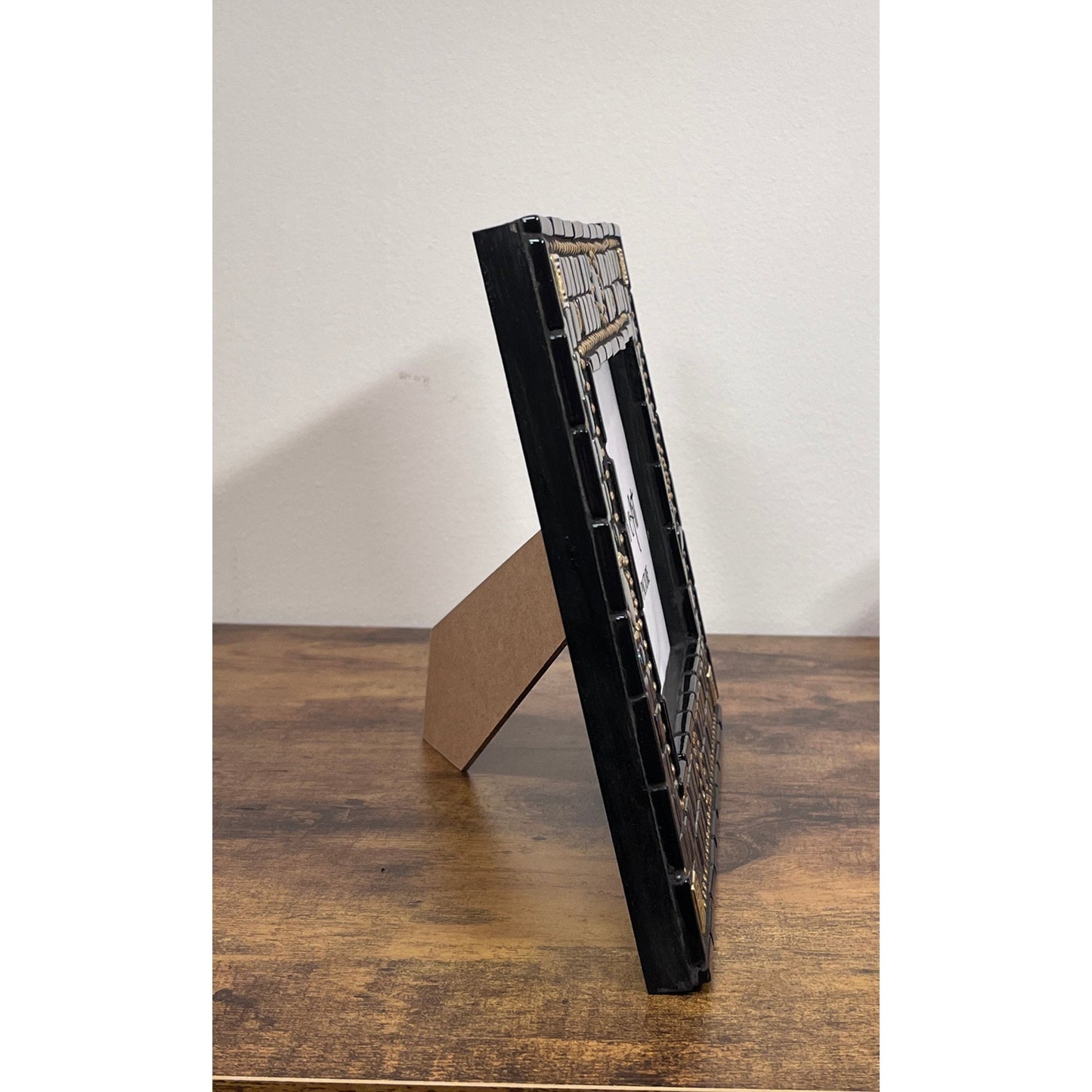 side of the frame:
5x7 black opal iridescent mosaic tiles with thin black tile outlining the outside as well as the opening for the photo. There are gold square tiles for highlights as well as bronze chain.