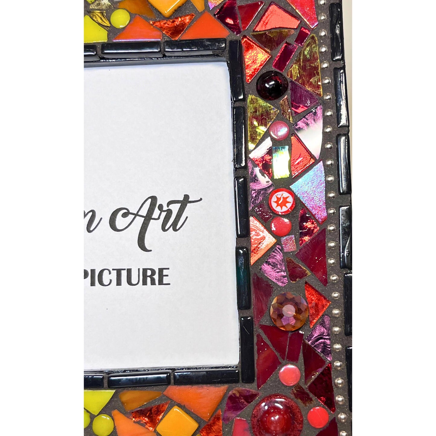 right side close up
5x7 photo frame in a rainbow of colors. Quite a big of texture with different heights and sizes of files. Glass, stained glass ad ceramic. Black outter border with silver chain inlay