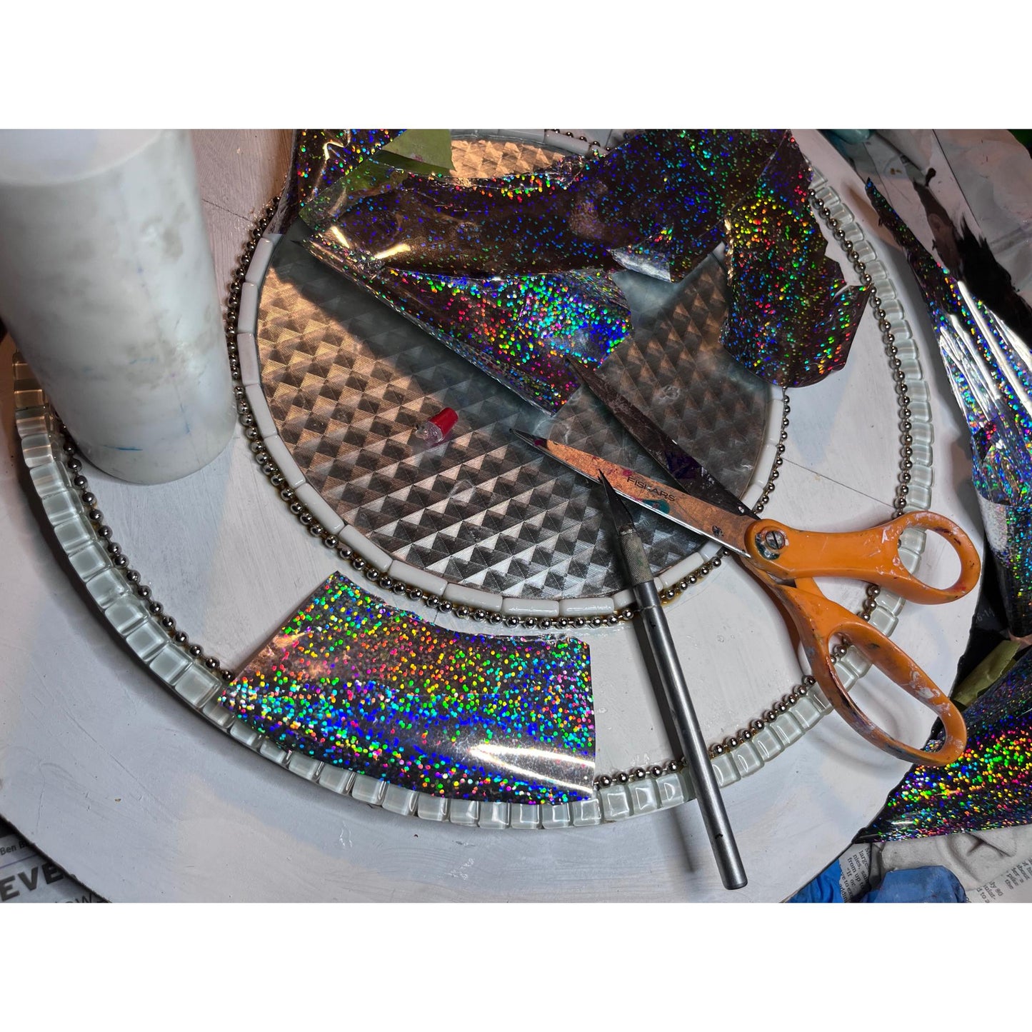 work in process photo of fantasy garden (rainbow) mirror. This picture shows the applying of silver holographic foil to be used in background of the hand-colored tempered glass