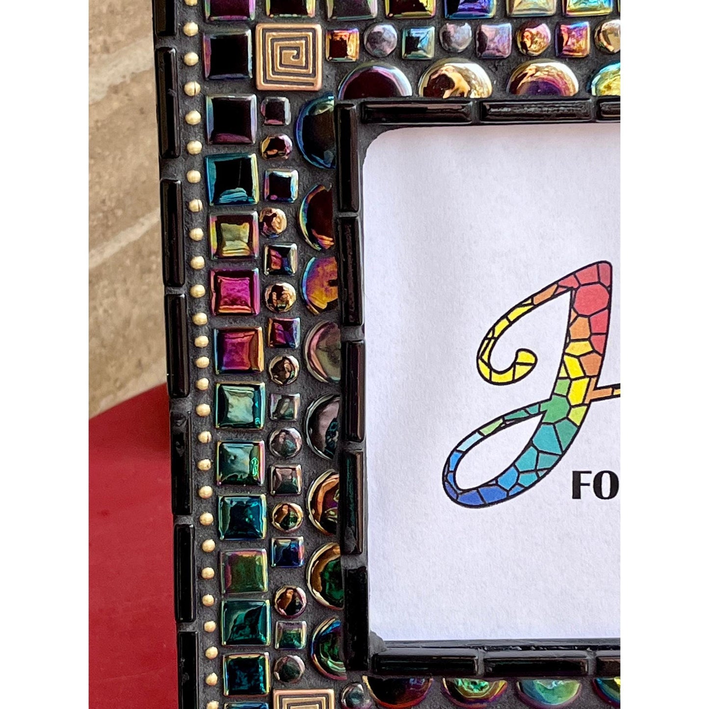left side close up
5x7 black opal iridescent mosaic tiles with thin black tile outlining the outside as well as the opening for the photo. There are gold square tiles for highlights as well as bronze chain.
