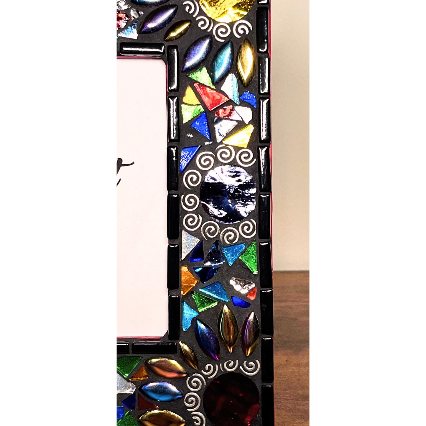 Right Side View:
Round Mirrored tiles with tibetan silver bead outlines.  Iridescent Leaves and assorted colored glass tile triangles.  Border of the Mirror is in black as is the grout color.