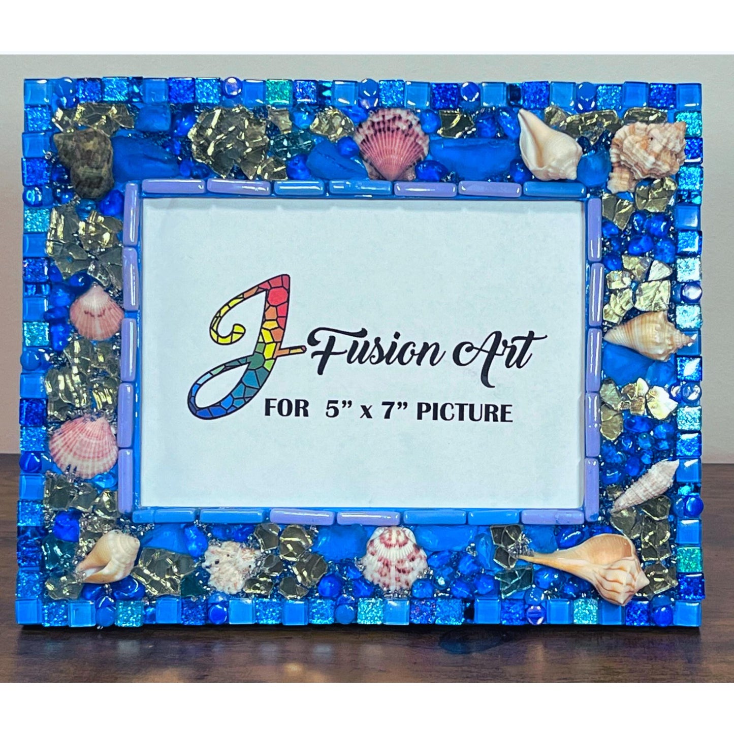 Front of five by seven photo frame with edges done in blue shades of glass and metallic tiles, beach glass, glass, rounds gold reflective glass, Natural Sea Shells, Grouted with blue, silver and gold seed beads mixed with resin