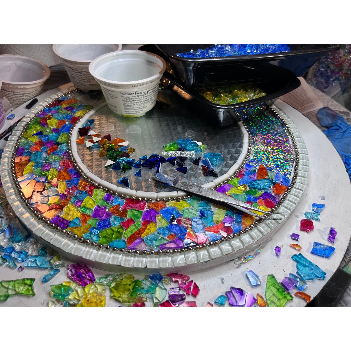 work in process photo of fantasy garden (rainbow) mirror. This picture shows the the hand-colored tempered glass being applied to the foil background.