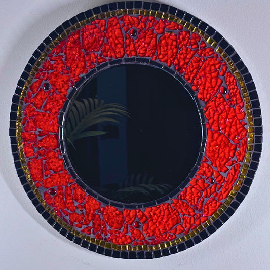 14 inch wood round with 8 inch beveled mirror.  Outside perimeter in black glass tiles outlined with gold mirror tile.  The center mirror is outlined in thin black glass tiles.  The remainder of the mirror is in red hand-tinted tempered glass,  Under the translucent glass are layers of fabric ribbon, glitters and foils